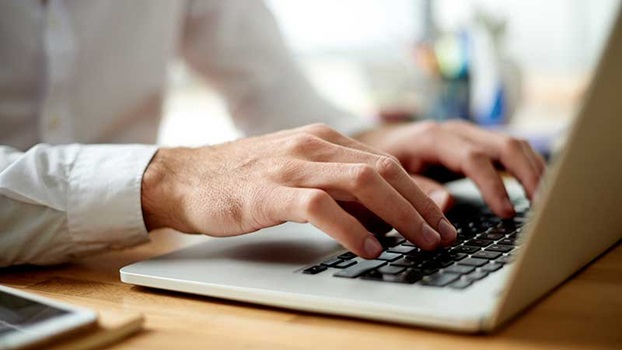 Homem a teclar no computador portátil